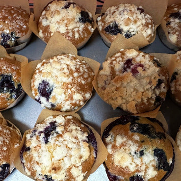 Blueberry muffins with crumb topping arranged in a grid on a gray surface.