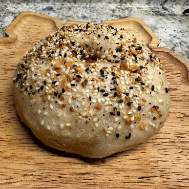 Round bagel of bread with sesame seeds on a wooden cutting board