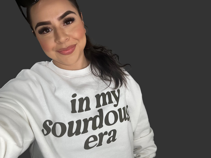 Person wearing a white sweatshirt with text, standing against a plain background