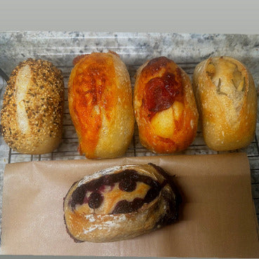 Five different types of bread on a cooling rack with a gray background